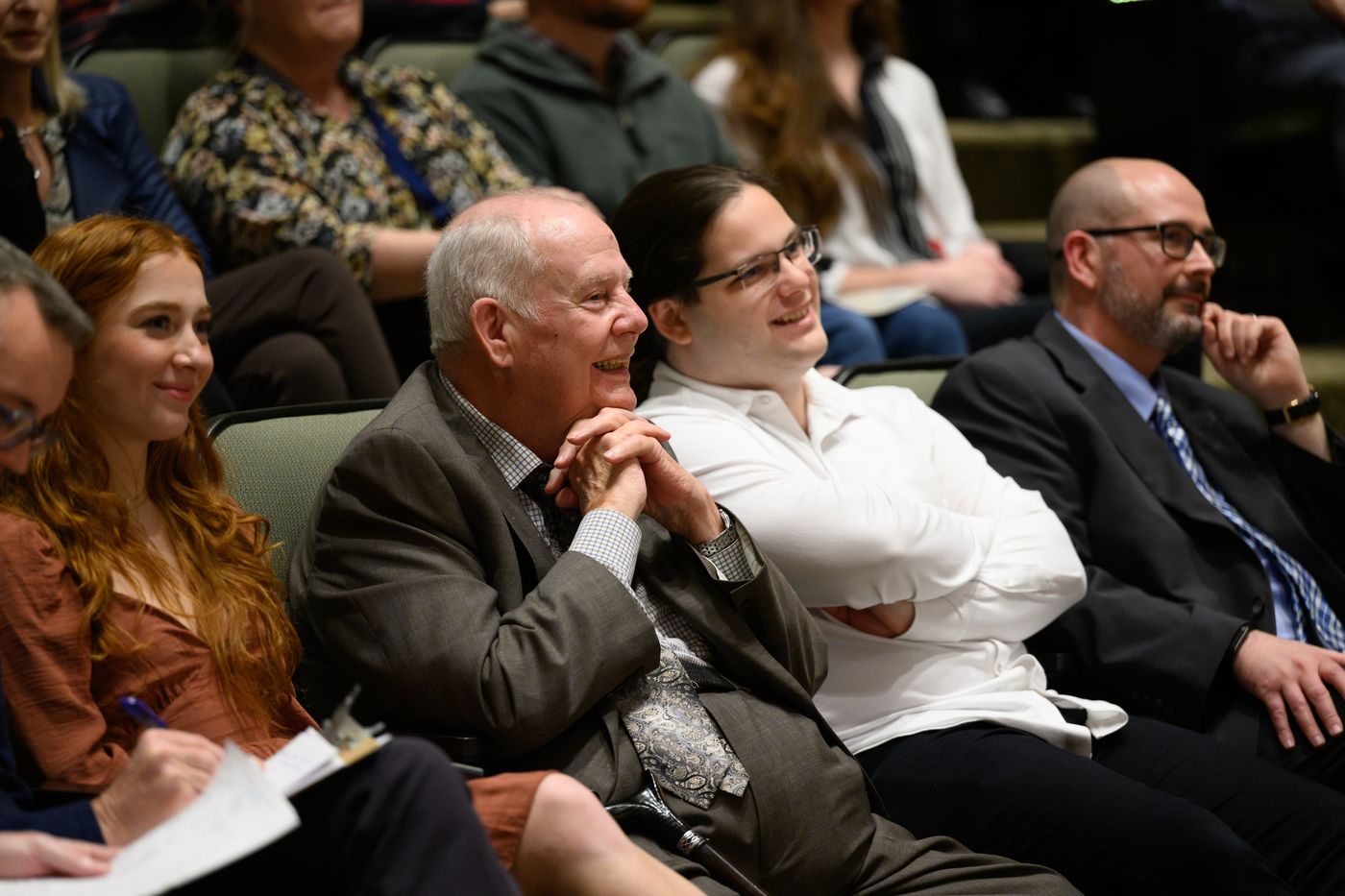 Mae Dingley, Dr. Allan Louden, Cole Wolfe, and Dr. Jarrod Atchison smile from the front row of the audience.